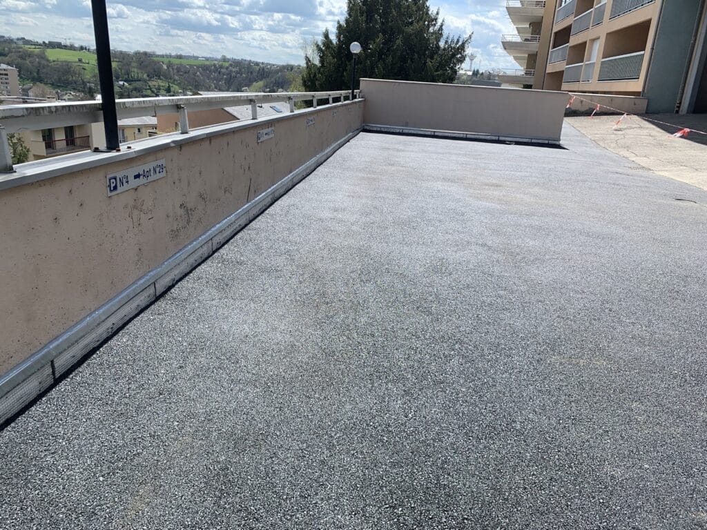 Parking extérieur avec terrasse et vue panoramique Parking en terrasse avec bitume gris, marquage P N°4 Apt N°29, garde-corps et vue panoramique sur les collines.